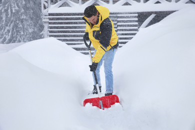 Man cleaning snow with shovel near house