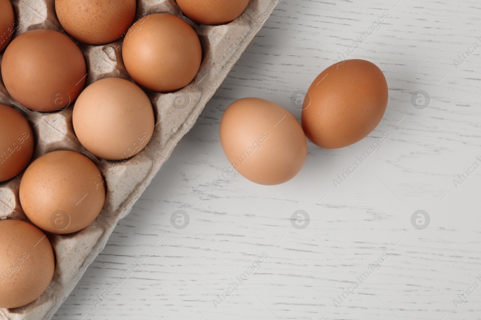 Photo of Raw chicken eggs on white wooden table, flat lay