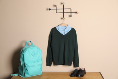 Photo of Shirt, backpack and jumper near beige wall. School uniform