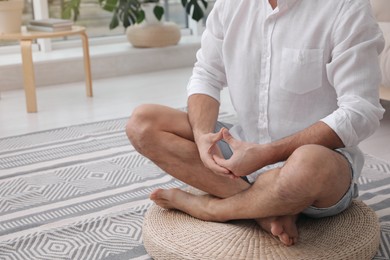 Photo of Man meditating on wicker mat at home, closeup