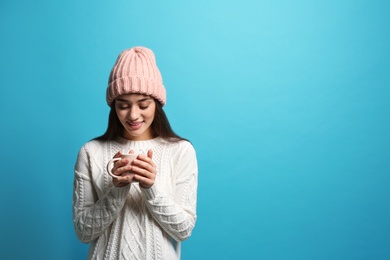 Young woman in sweater with cup of hot coffee on color background, space for text. Winter season
