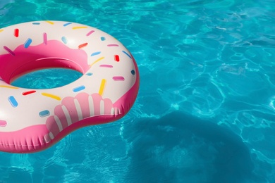 Inflatable ring floating in swimming pool on sunny day. Space for text