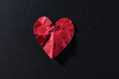 Photo of Red crumpled paper heart on black background, top view. Breakup concept