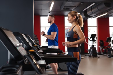 Beautiful couple training on treadmills in gym