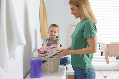 Photo of Mother and daughter taking out dirty clothes from basket in bathroom, space for text