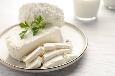 Photo of Delicious fresh cottage cheese with parsley on white wooden table, closeup