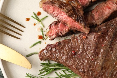 Photo of Delicious grilled beef steak and rosemary on plate, top view