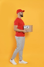 Photo of Courier holding cardboard box on yellow background