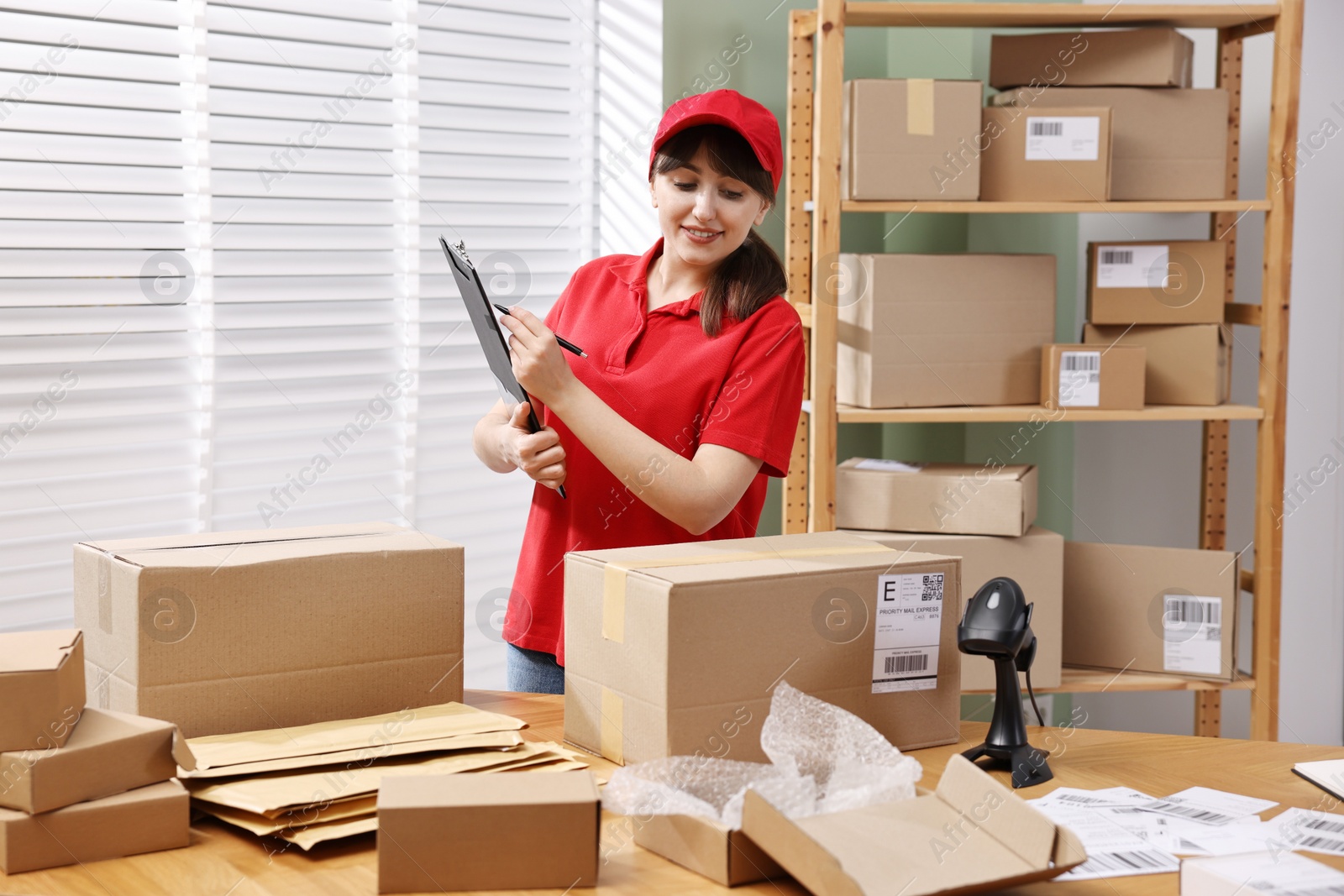 Photo of Parcel packing. Post office worker with clipboard at wooden table indoors