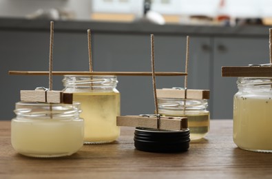 Glass jars with melted wax on wooden table indoors. Handmade candles