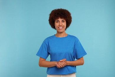 Portrait of happy young woman on light blue background