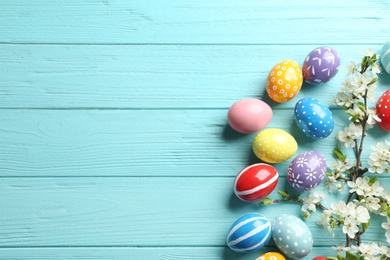 Flat lay composition with painted Easter eggs and blossoming branches on wooden background. Space for text