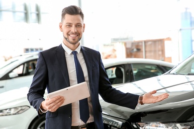 Photo of Salesman with tablet in salon. Buying new car