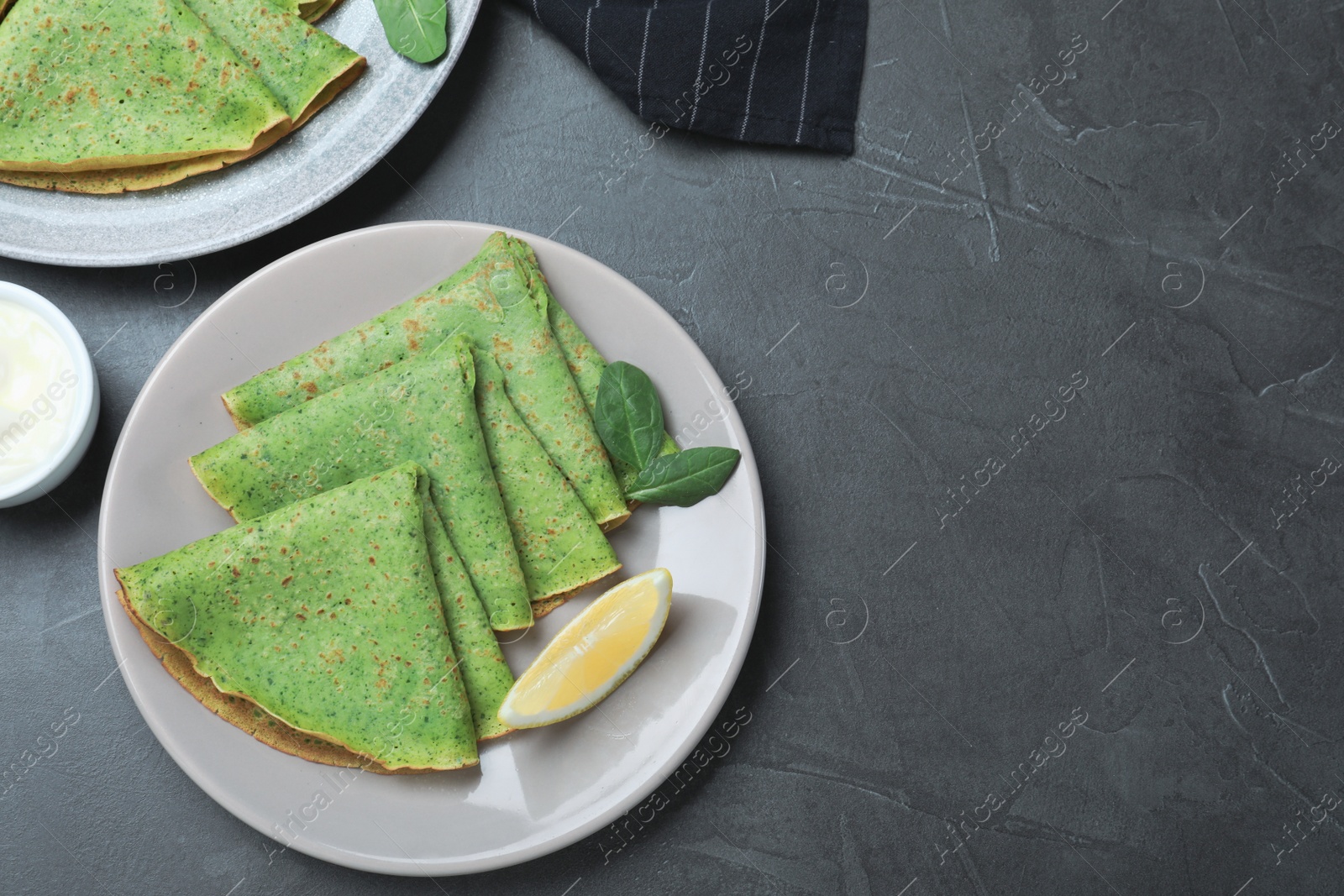 Photo of Tasty spinach crepes served on grey table, flat lay. Space for text