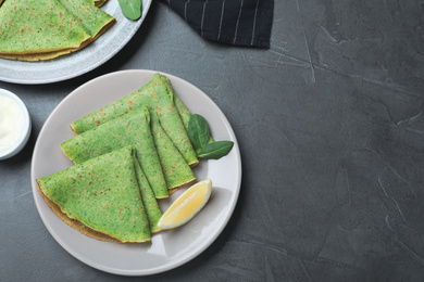 Tasty spinach crepes served on grey table, flat lay. Space for text