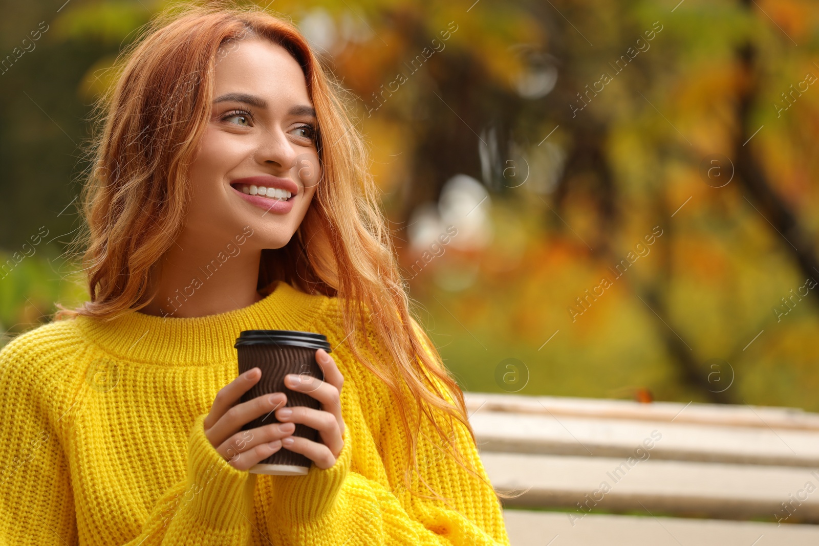 Photo of Portrait of smiling woman with paper cup enjoying autumn outdoors. Space for text