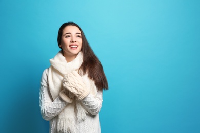 Young woman wearing warm clothes on color background, space for text. Winter season