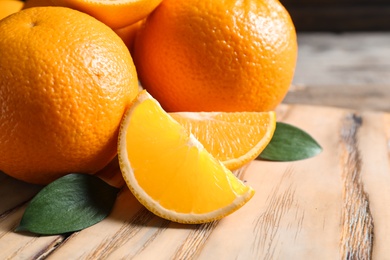 Fresh oranges with leaves on wooden table, closeup. Space for text