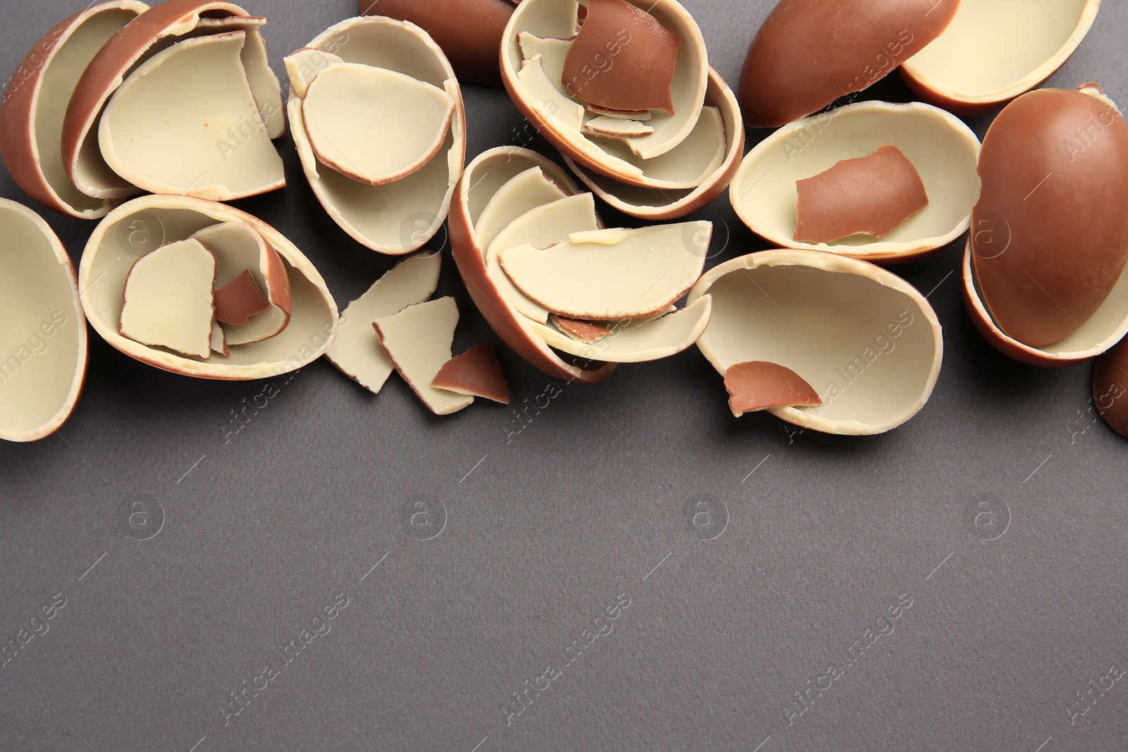 Photo of Sveti Vlas, Bulgaria - July 3, 2023: Broken halves of Kinder Surprise Eggs on grey background, flat lay. Space for text