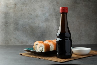 Photo of Tasty soy sauce and sushi rolls with salmon on grey table. Space for text