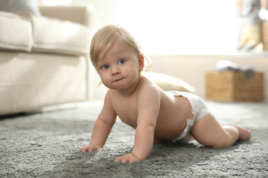 Photo of Cute little baby in diaper on carpet at home