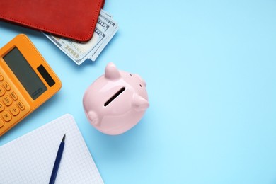 Photo of Piggy bank, notebook, calculator and wallet with banknotes on light blue background, flat lay. Space for text