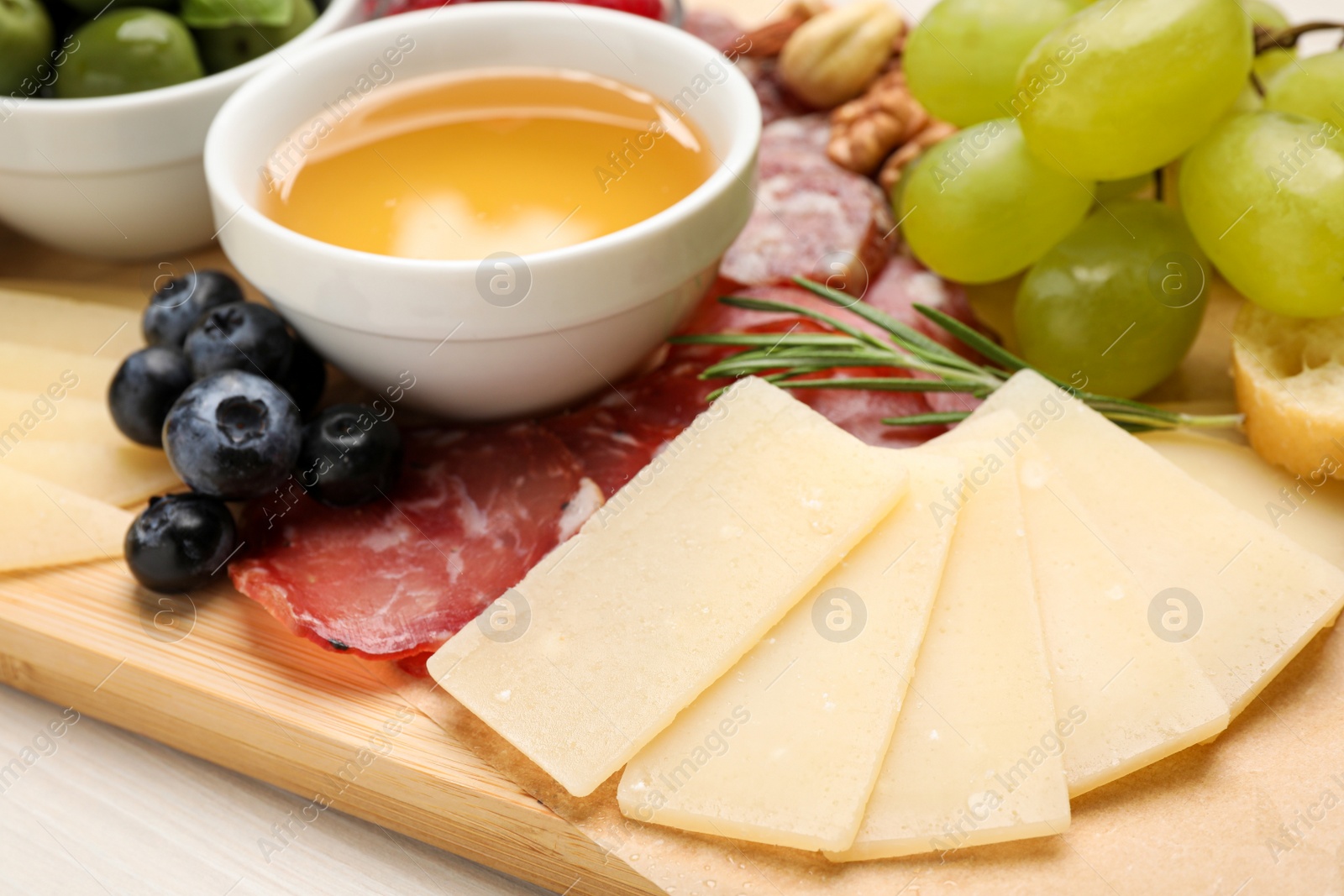 Photo of Snack set with delicious Parmesan cheese on wooden board, closeup