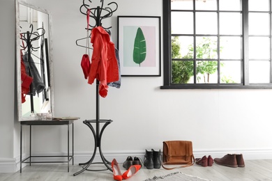 Modern hallway interior with clothes on hanger stand and mirror