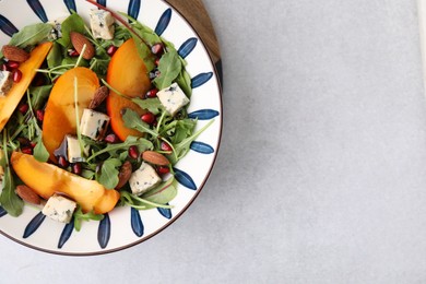 Tasty salad with persimmon, blue cheese, pomegranate and almonds served on white table, top view. Space for text