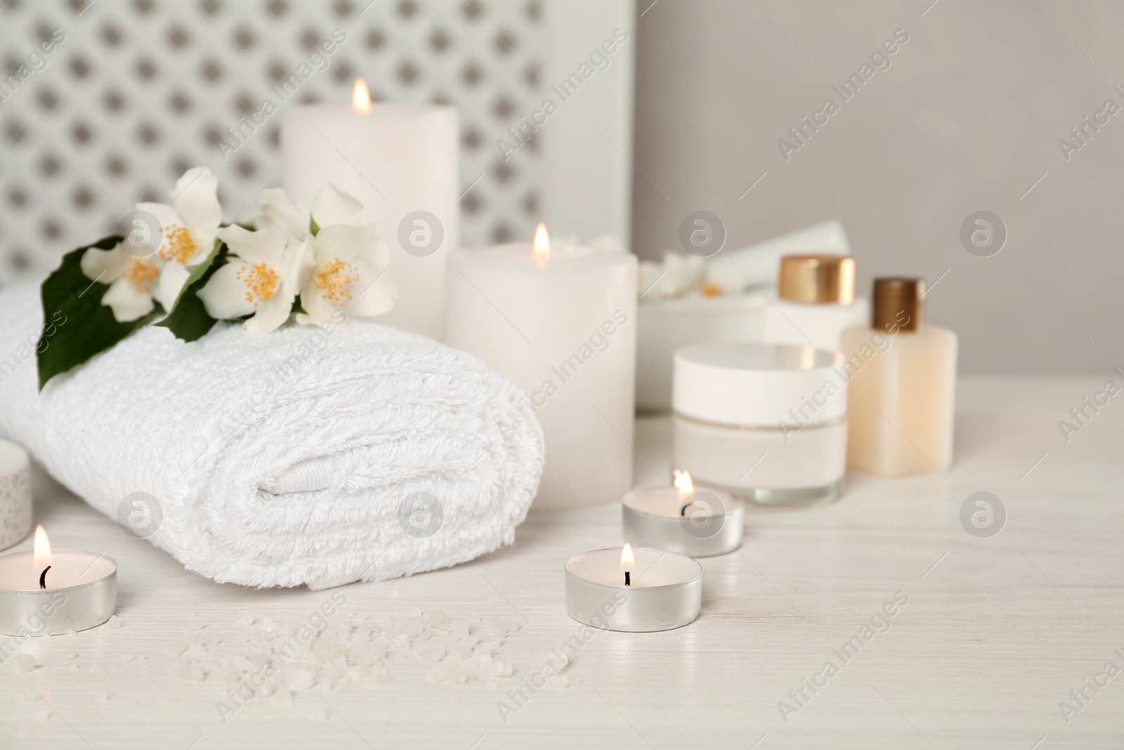 Photo of Composition with beautiful jasmine flowers and burning candles on white wooden table