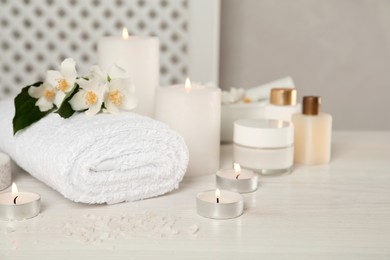 Photo of Composition with beautiful jasmine flowers and burning candles on white wooden table