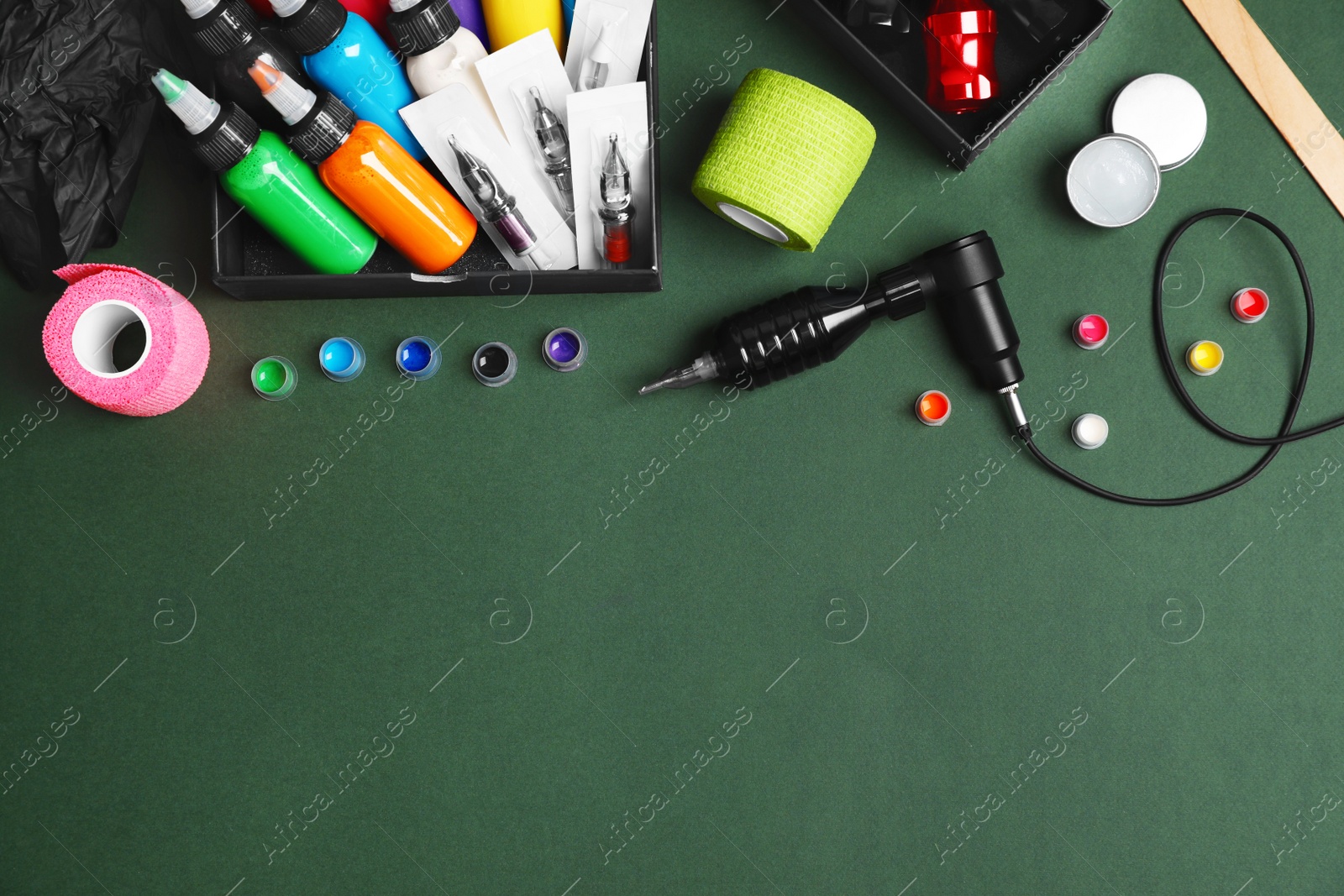 Photo of Flat lay composition with tattoo equipment on dark green background. Space for text