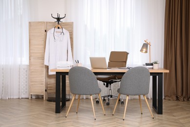 Modern medical office interior with doctor's workplace and chairs