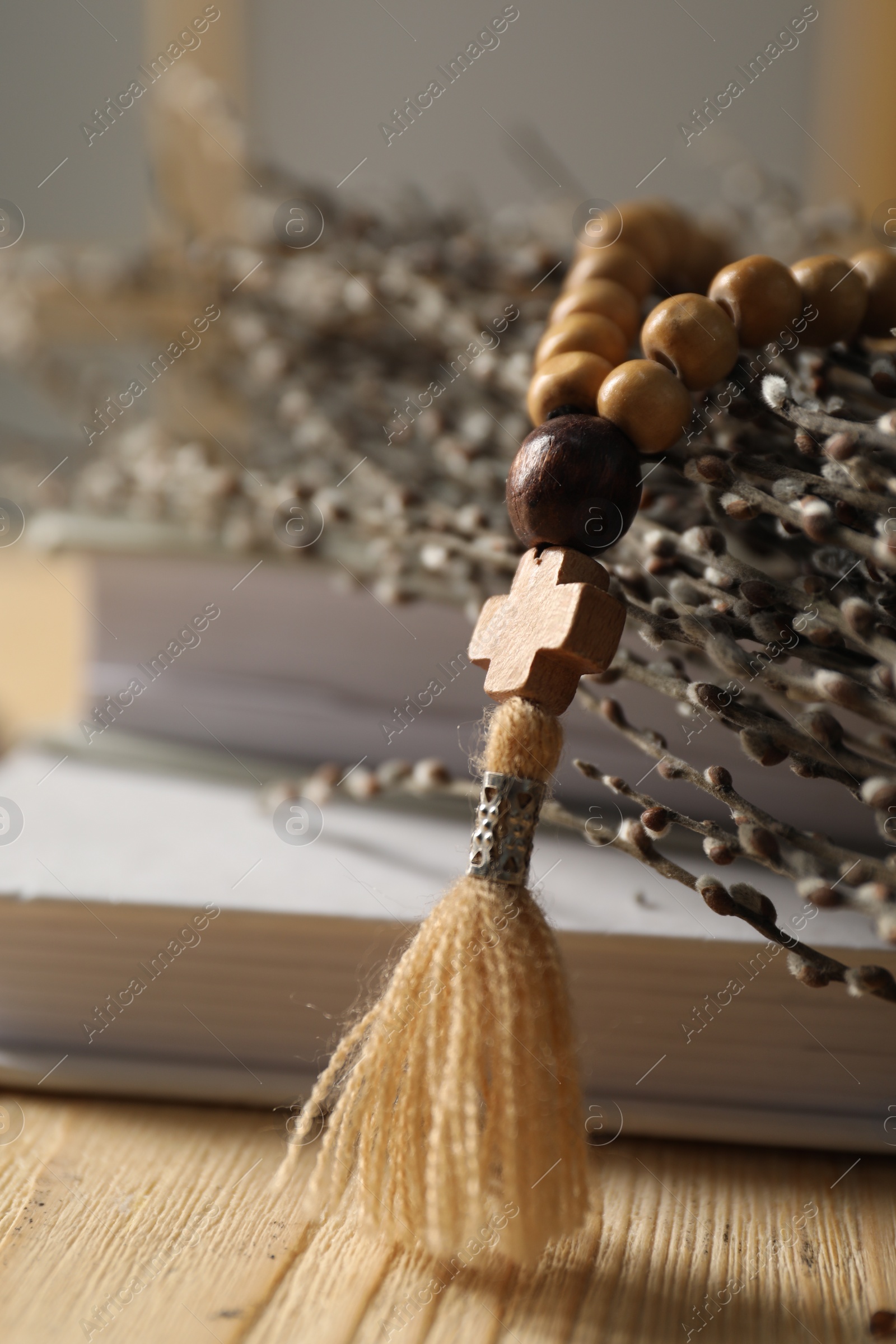 Photo of Rosary beads, books and willow branches on table, closeup