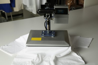 Photo of Printing logo. Heat press with t-shirt on white table