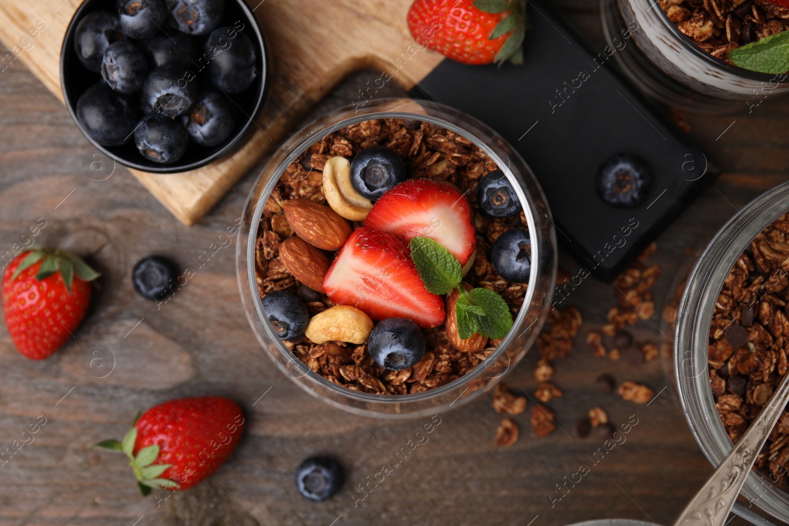 Photo of Tasty granola, berries and nuts on wooden table, flat lay