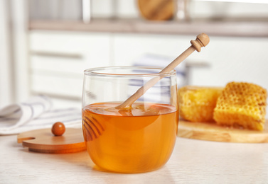 Glass jar of honey on white wooden table