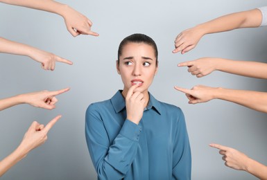 Photo of People pointing on emotional businesswoman against light grey background. Corporate social responsibility concept