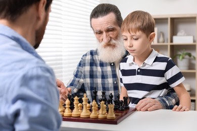 Family playing chess together at table in room