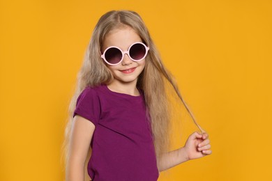 Photo of Girl in stylish sunglasses on orange background