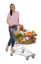 Happy woman with shopping cart full of groceries on white background