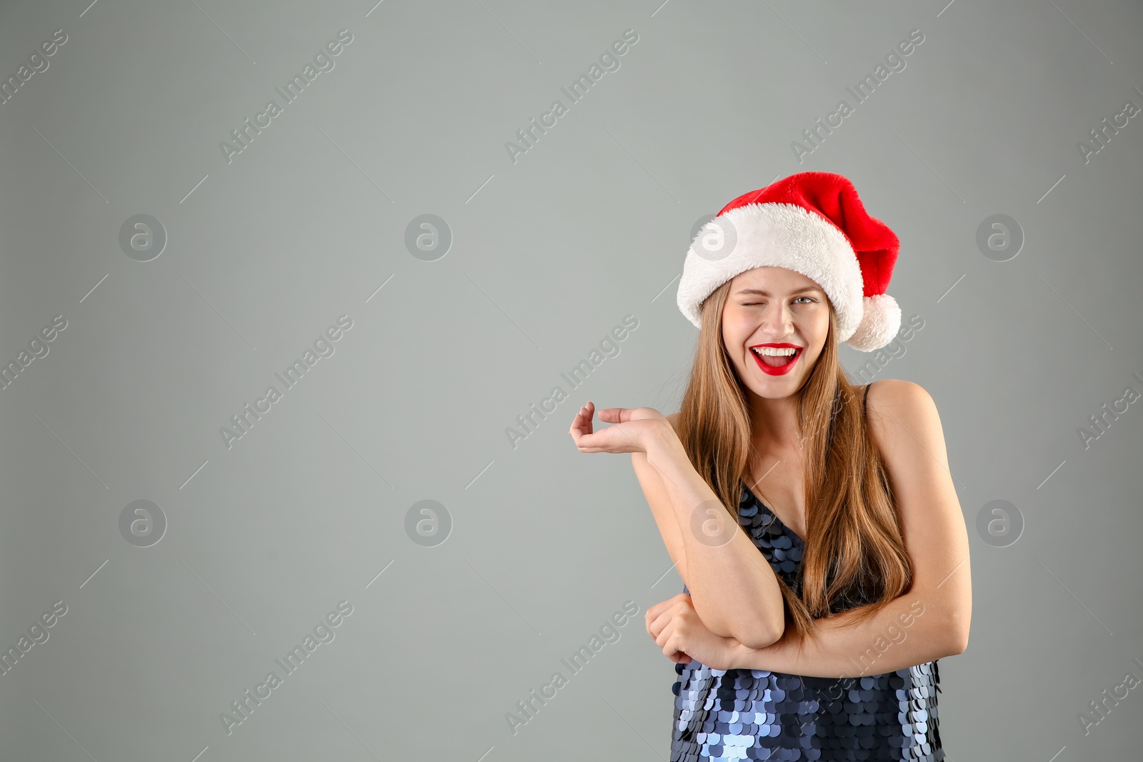 Photo of Young beautiful woman in Santa hat on grey background. Christmas celebration