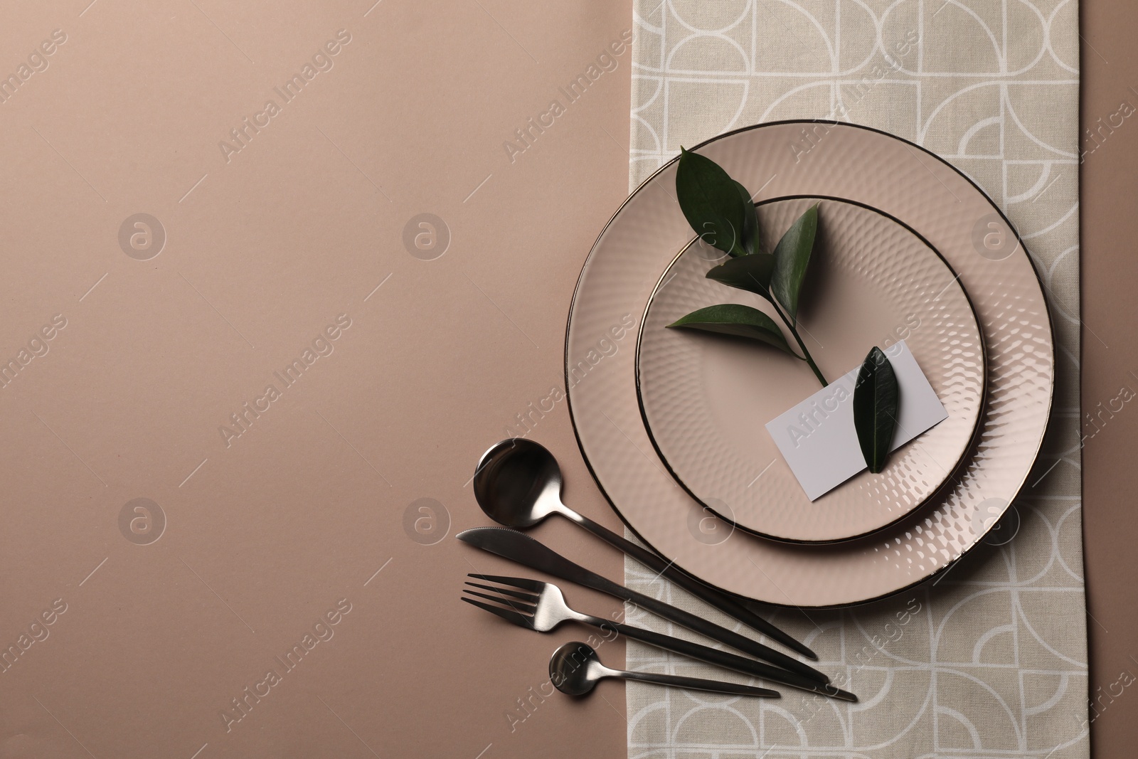 Photo of Stylish table setting. Plates, cutlery, blank card and green twig on beige background, top view with space for text