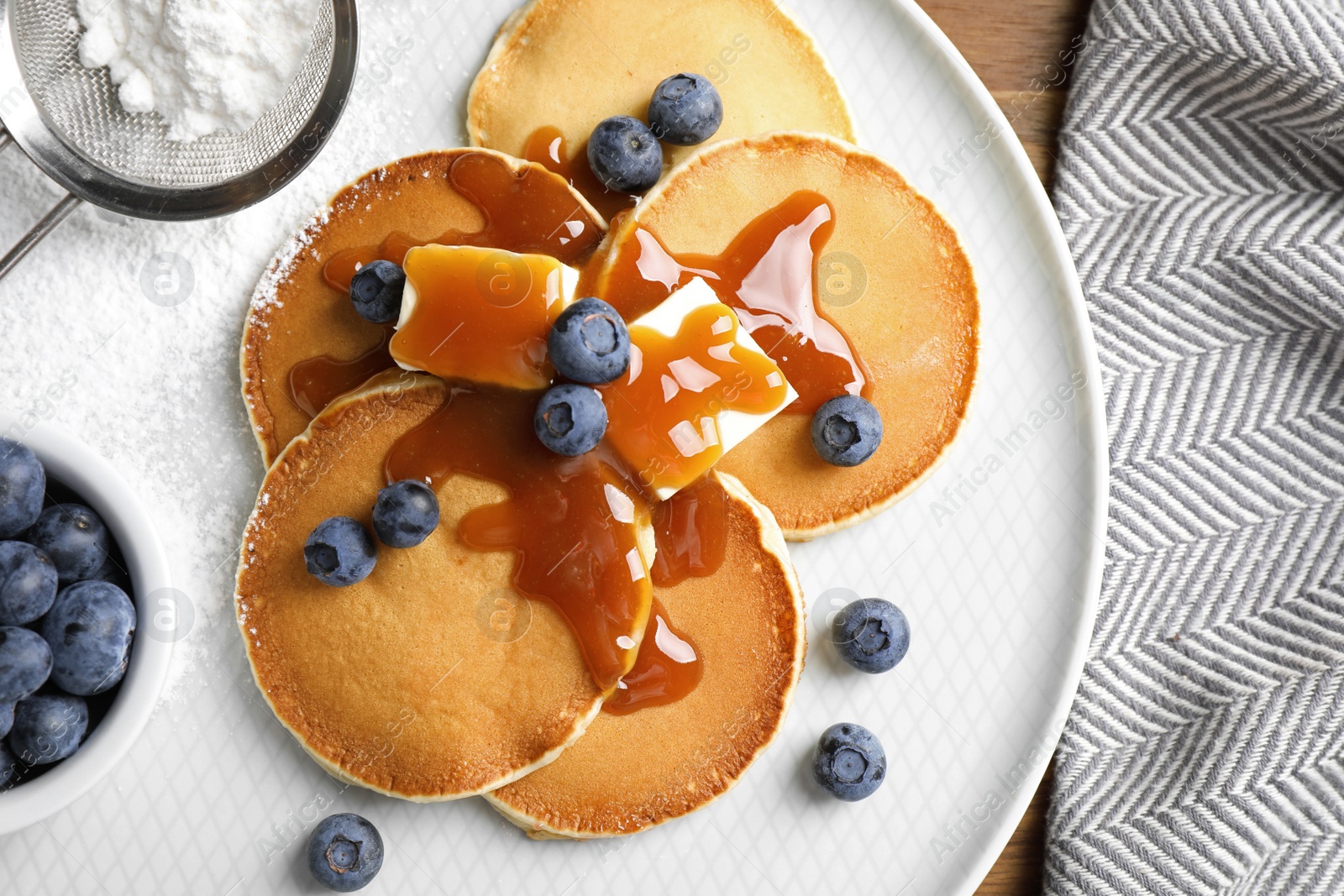 Photo of Tasty pancakes with blueberries served on wooden table, flat lay