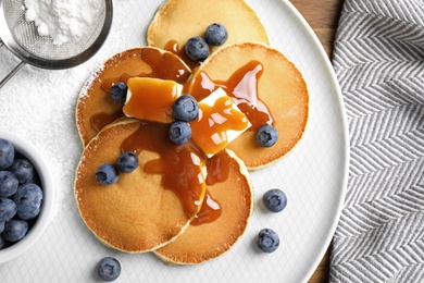 Tasty pancakes with blueberries served on wooden table, flat lay