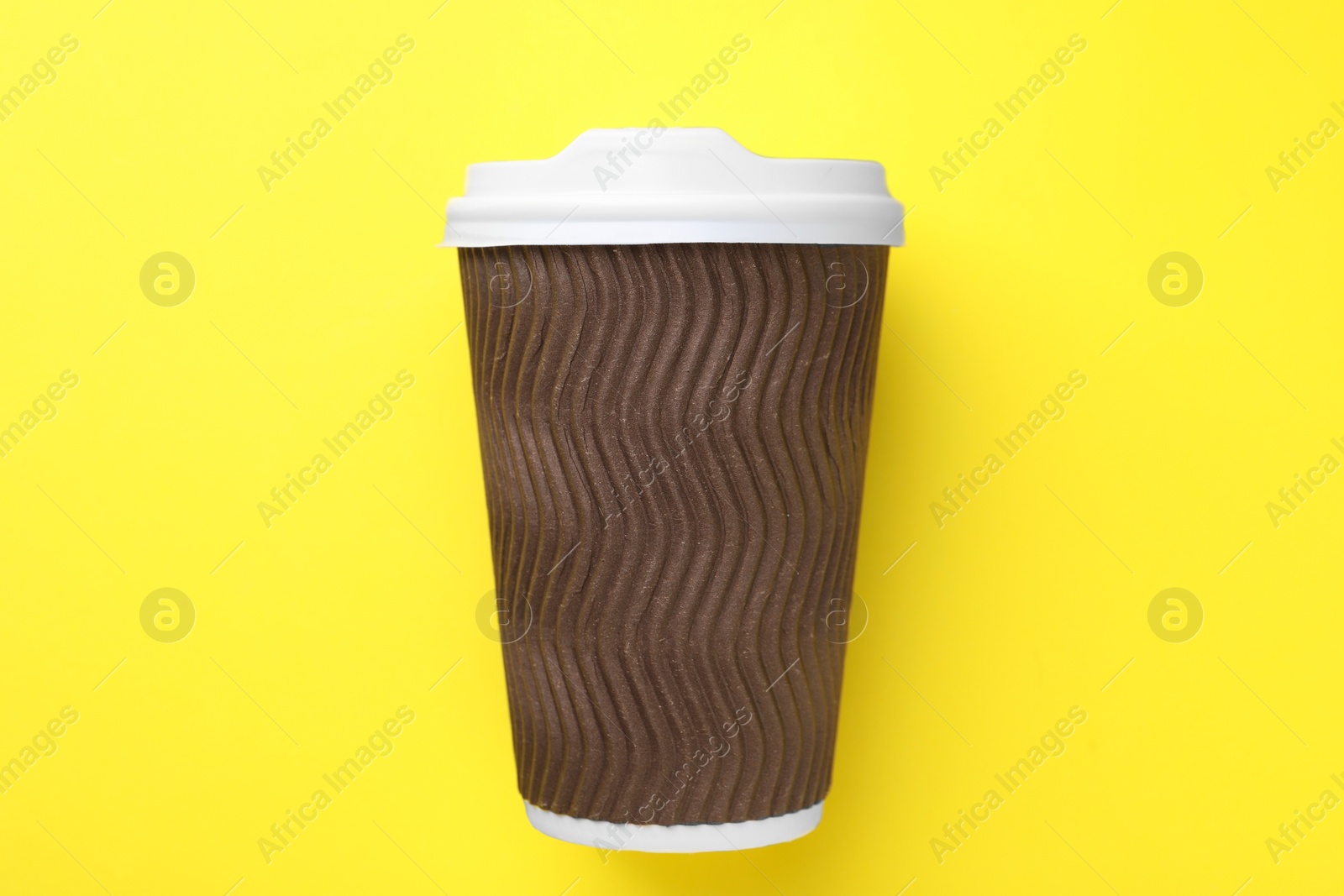 Photo of One paper cup on yellow background, top view. Coffee to go