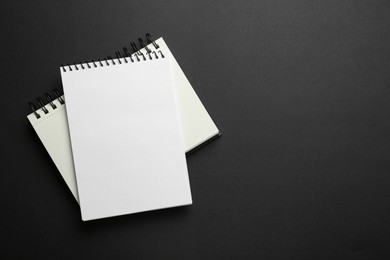 Photo of Notebooks on black background, top view. Space for text