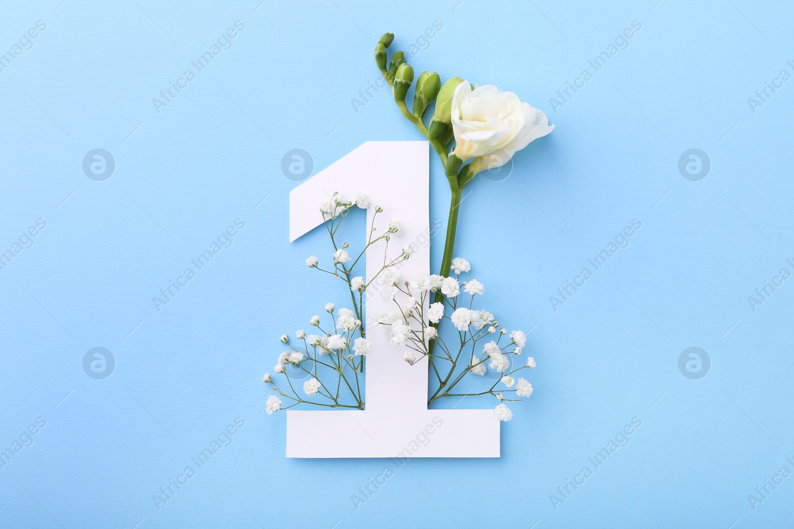 Photo of Paper number 1 and beautiful flowers on light blue background, top view