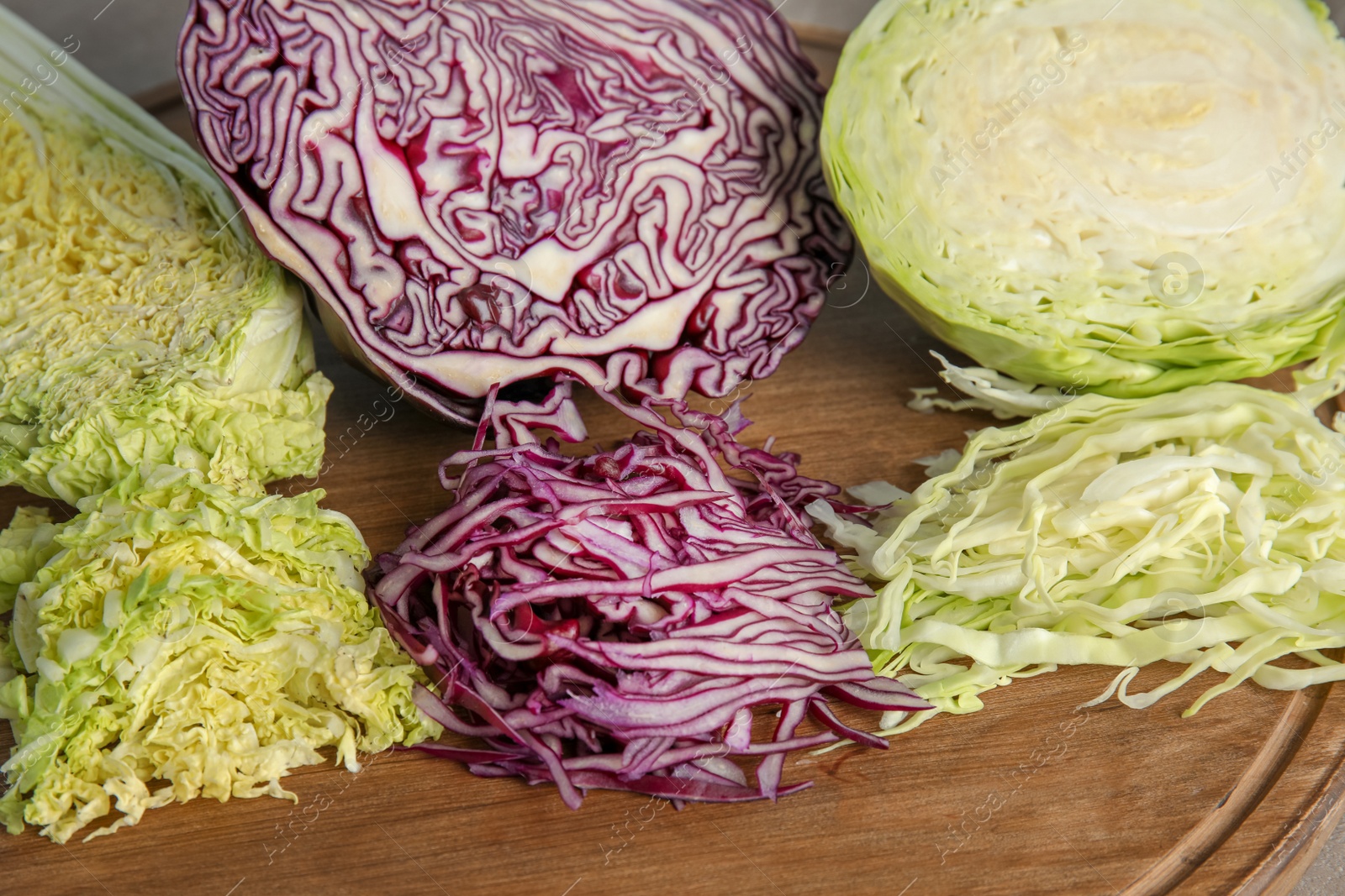 Photo of Different sorts of cabbage on wooden board, closeup