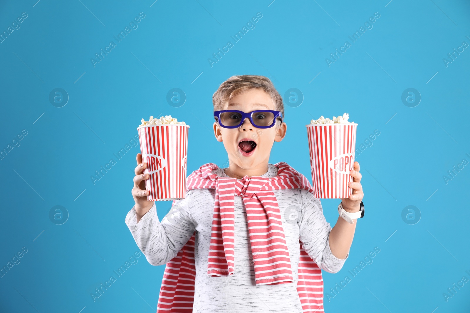 Photo of Cute boy in 3D glasses with popcorn buckets on color background